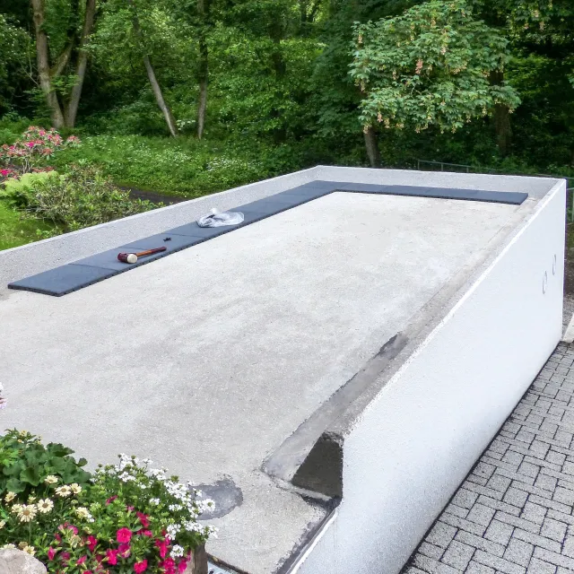 Les dalles de terrasse grises de WARCO sont posées sur le toit en béton du garage situé à côté du bâtiment résidentiel.