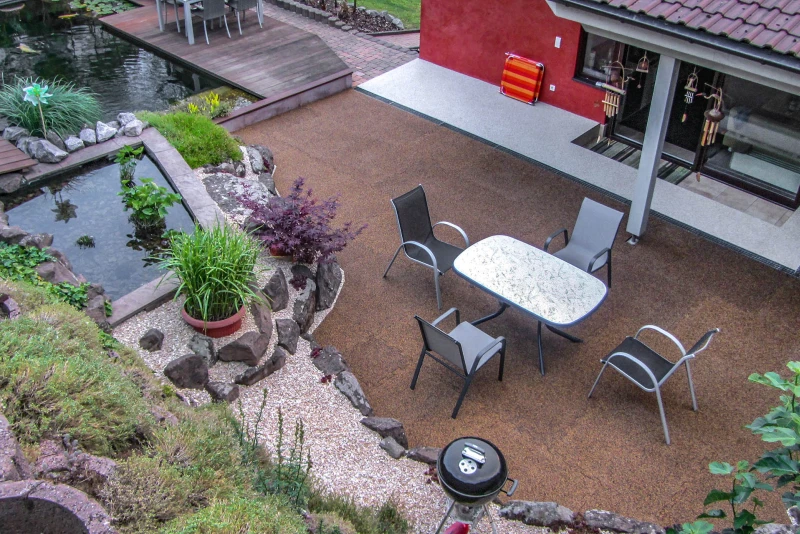 Sur un toit-terrasse, couvert de dalles WARCO carrés de couleur Maroc, se trouve un coin salon avec des agrumes.