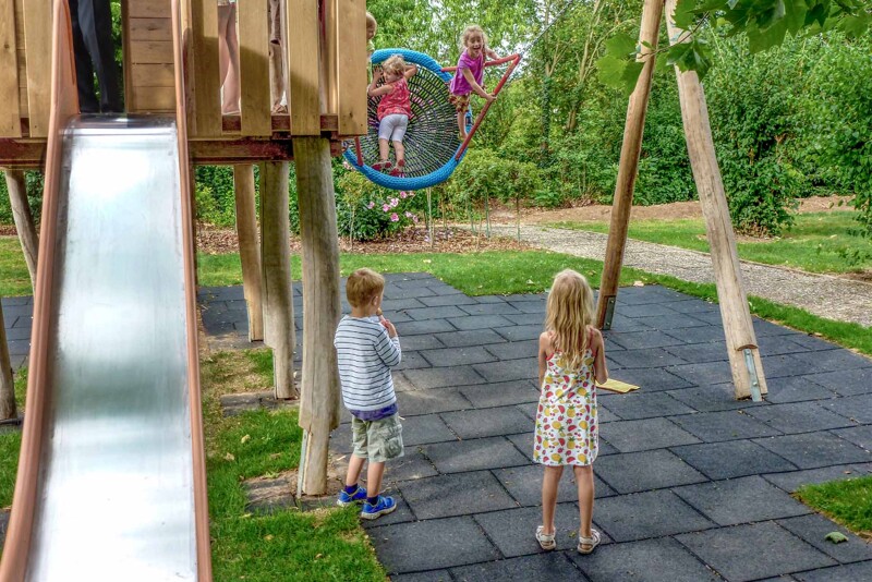 Les enfants jouent sur une aire de jeux composée de la balançoire, de la maison escalade, du toboggan et des dalles antichoc