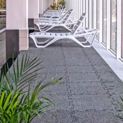 Le carrelage WARCO en couleur granit clair installé dans un espace de repos avec les chaises longues dune piscine intérieure.