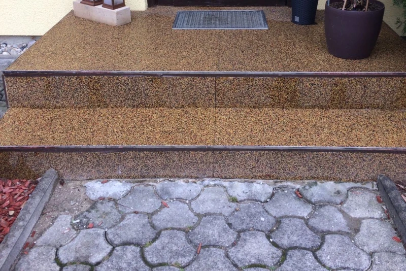 Der Eingangsbereich zu einem Einfamilienhaus wurde teilweise saniert. Die Treppe und das Podest wurden schon mit WARCO Boden im Farbdesign Terrakotta belegt. Der Weg zum Haus besteht noch aus Betonpflaster.