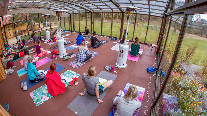 Yogaraum mit rotbraunen Warco-Matten, in dem viele Yoga-Schüler ihre Matten ausgebreitet haben und ihre Übungen machen.