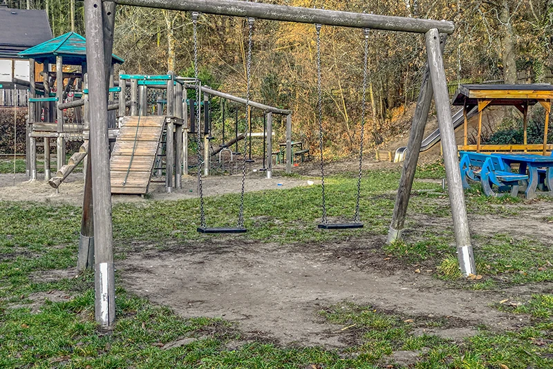 Un sol recouvert d'herbe ne convient pas comme protection contre les chutes sur un terrain de jeu public. Le gazon sous la balançoire est abimé.