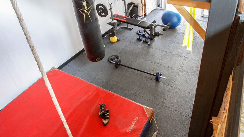 Une salle de gym privée à domicile. Sur les tapis noirs de fitness de WARCO il y a différents appareils pour entraînement.