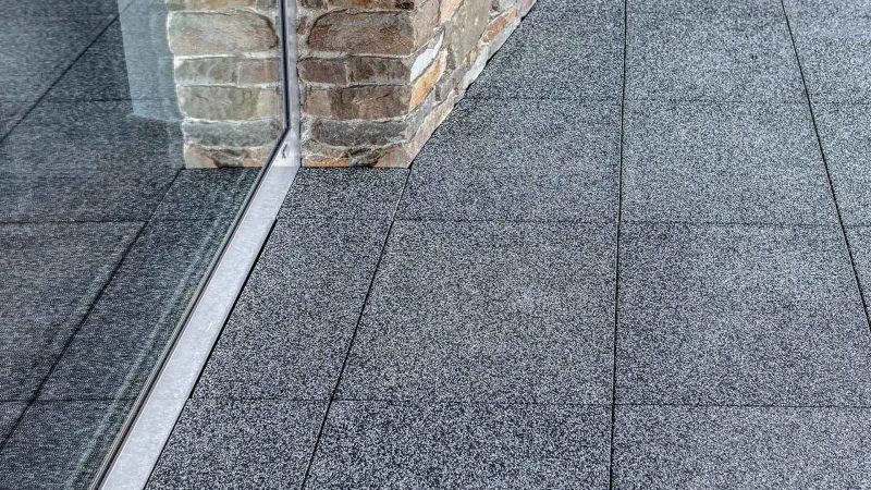 Les dalles terrasse WARCO, coupées sur mesure avec précision, sont posées à coté de mur de forme irrégulière.