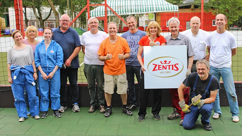 À la fin du travail, une équipe de Zentis se met en rang pour une photo souvenir. Les femmes et les hommes se tiennent sur le sol d'exposition en caoutchouc vert de WARCO.
