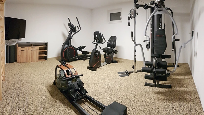 La salle de gym à domicile avec des équipements de musculation est recouverte de tapis sportifs en Travertin type puzzle de WARCO.